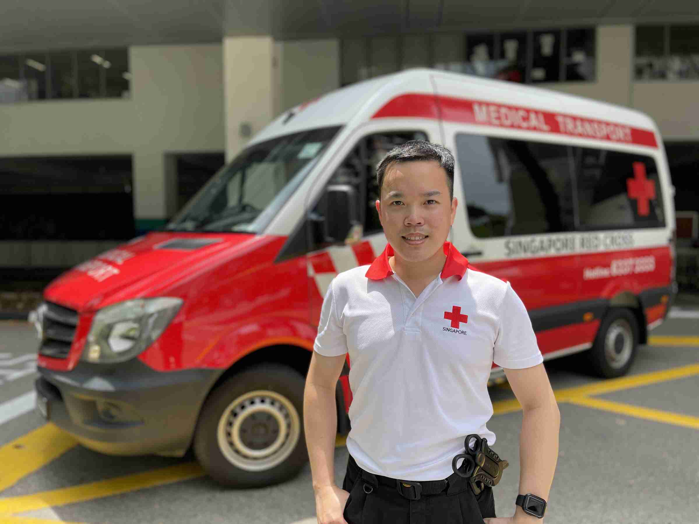 Photo of volunteer Chay Him standing in front of a Singapore Red Cross vehicle