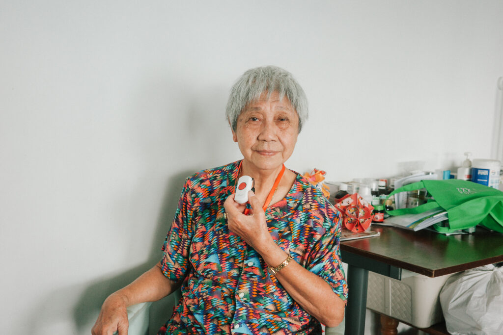 Elderly beneficiary holding up a HoME+ device