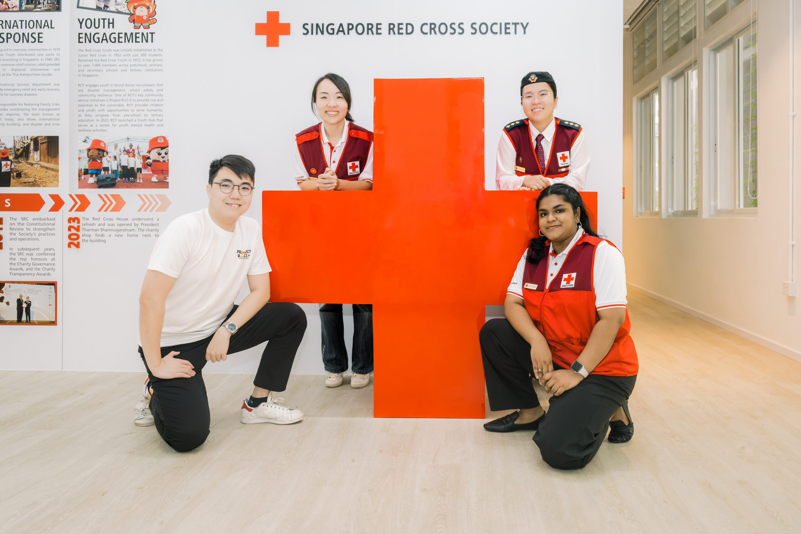 Red Cross Youth Volunteers posing for a photo by the Singapore Red Cross logo